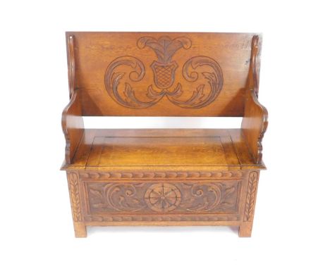 A 17thC style oak monks bench, with a carved top, and frieze to the front, raised on square legs, 77cm H, 106cm W, 47cm D.