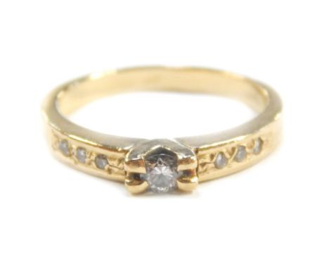 A diamond solitaire ring, with channel diamond set shoulders, in yellow metal, size M, 3.8g.