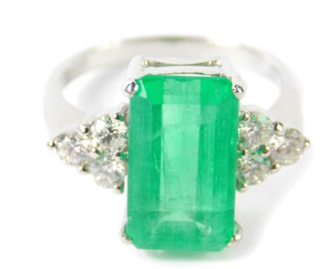 An 18ct white gold emerald and diamond ring, the faceted rectangular cut emerald approx 4.7ct, flanked by six brilliant cut d