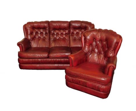 A Mansfield Upholstery red leather three seater sofa, with button back cushions, raised on castors, 180cm W, together with a 