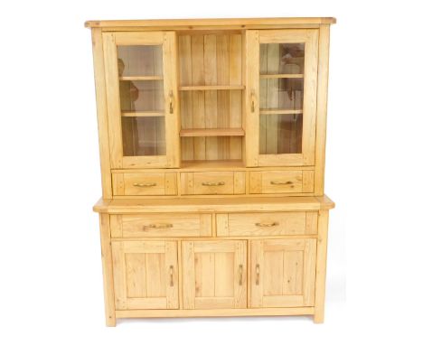 A light oak kitchen dresser, with three shelves, flanked by two glazed doors, enclosing shelves over three drawers, above two