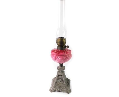 A Victorian silver painted cast iron oil lamp, with a pink to ruby opaline glass reservoir, with chimney, 66cm H.
