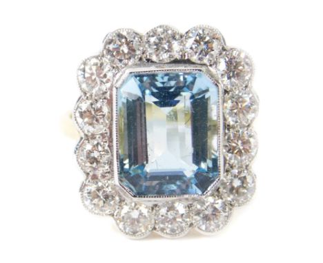 An 18ct gold aquamarine and diamond ring, the rectangular cut aquamarine in a surround of 14 brilliant cut diamonds, aquamari