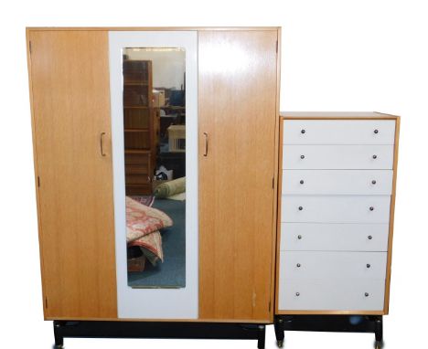 A G-Plan 1950's light oak and cream painted double wardrobe, with a mirrored central section, flanked by two doors, raised on