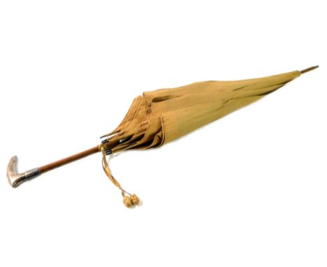 A French early 20thC tan coloured silk parasol, wooden shafted, with a silver handle, and outer case, 89cm L.