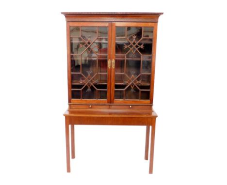 A Chippendale style mahogany bookcase on stand, the outswept pediment with dentil moulding and blind fretwork, over two astra