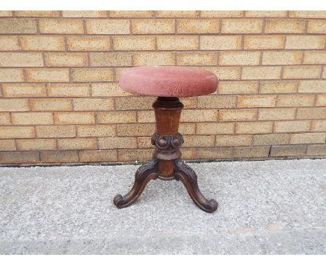 A rise and fall piano stool on carved tripod supports.