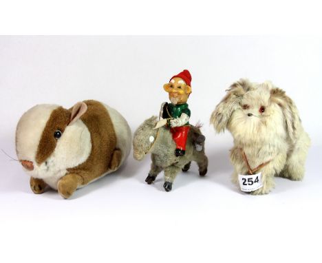 A vintage tin plate mechanical toy of a gnome riding a donkey, with a Merrythought rabbit and a fur covered Pekingese dog toy