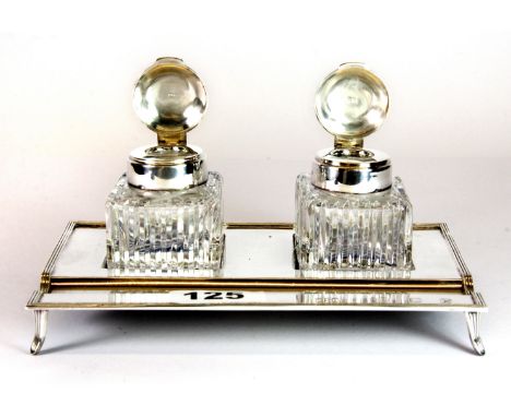 A late 20th century hallmarked silver twin bottle desk stand, with reeded border and integrated pen tray, raised on four shor