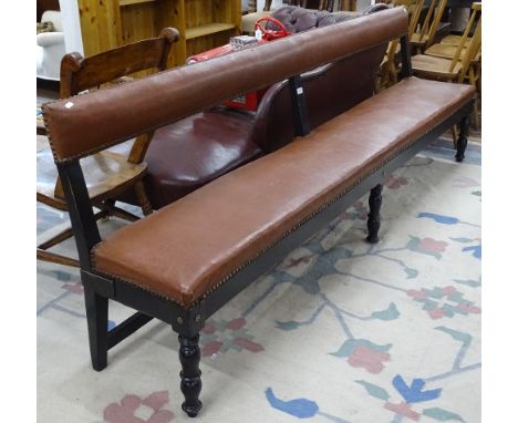 An early 20th century studded rexine upholstered and ebonised station waiting room bench, on turned legs, L230cm 