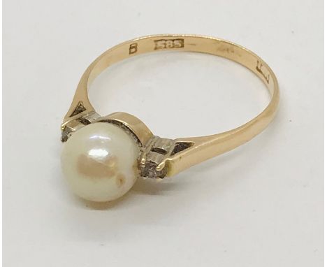 A 14ct gold ring set with a pearl flanked by two diamonds