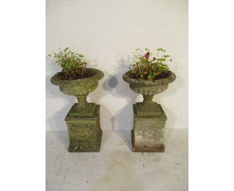A pair of concrete garden urns on plinths