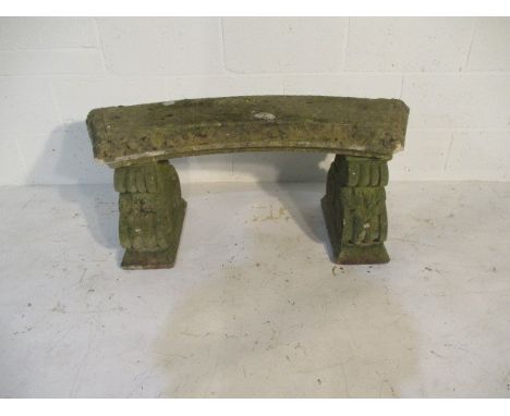 A curved concrete garden bench