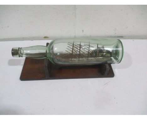 A four mast sailing boat in a bottle on wooden stand