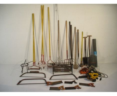 A collection of various tools and other items including spades, pitchforks, fire crate, saws, rakes etc