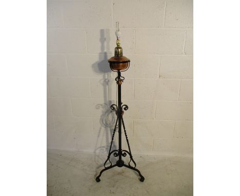 A floor standing brass lamp on decorative wrought iron stand H144cm