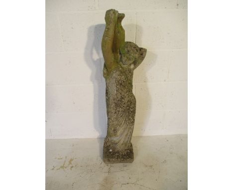 A concrete garden statue of a semi-nude lady carrying an urn