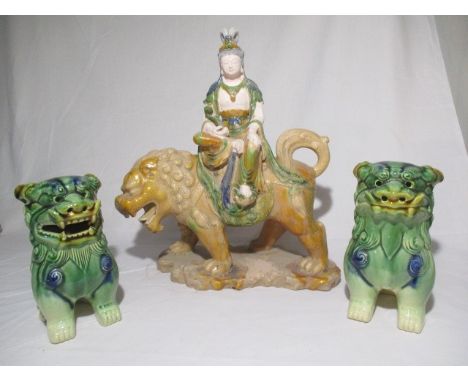 A porcelain figure of Chinese deity sat on a lion and two Foo dogs