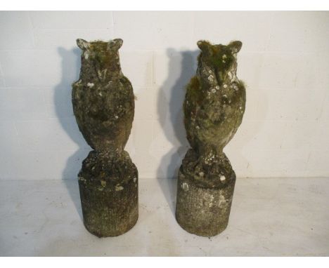 A pair of weathered concrete garden ornaments in the form of owls on granite plinths - overall height 105cm