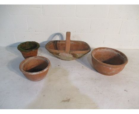 A terracotta pot in the form of a carry basket, along with three terracotta garden pots of various sizes