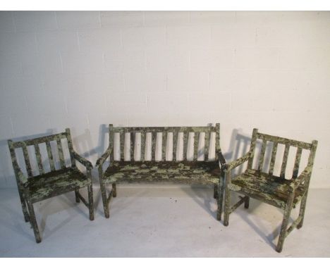 A well weathered wooden garden bench with two matching chairs