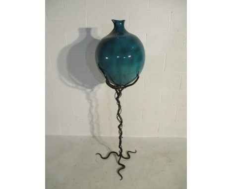 A large glazed pottery urn on intertwined wrought iron sculptural stand