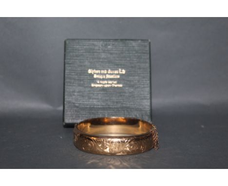 An early 20th century rose gold plated hinged bangle with engraved top and metal core. 6.5 cm diameter. (Slightly dented).
