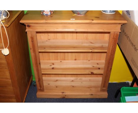 A modern pine open bookcase with moulded top above a plain frieze and two adjustable shelves all between in sized columns and