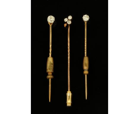 Three gold coloured metal and diamond set stick pins, two set with single stones (0.2 &amp; 0.15 carat respectively and the t