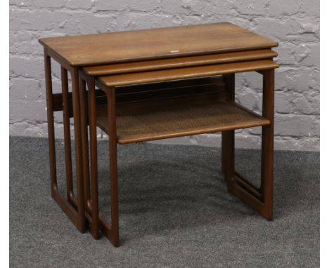 A carved nest of three teak occasional tables with lower rattan covered shelf.