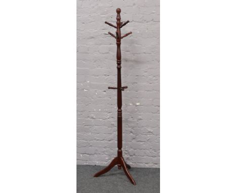 A turned coat stand raised on a tripod base.
