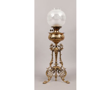 An ornate brass oil lamp base with clear and frosted glass shade, height without shade 62cm.