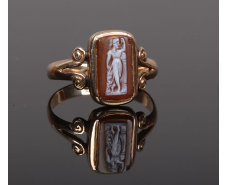 An early 20th century 9ct gold and carved hardstone cameo ring with split scroll shoulders. Size R.