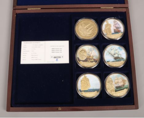 A cased set of HMS Victory gilt metal and enamel coins.