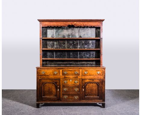 A George III oak dresser, with a matched rack with three shelves under a moulded cornice, the base with five drawers and two 