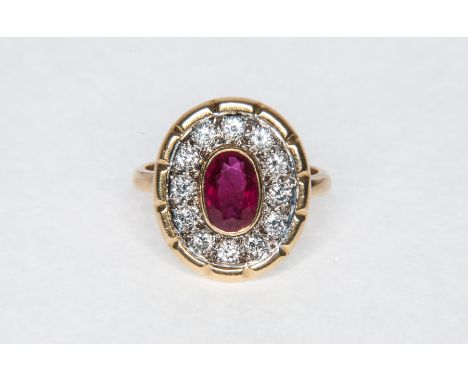 A ruby and diamond oval cluster ring, the oval cut ruby 7.2mm x 5mm collet set and surrounded by diamonds (12), brilliant cut