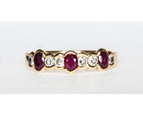 A modern ruby and diamond half eternity ring with three oval mixed cut rubies spaced by six brilliant cut diamonds all in a y