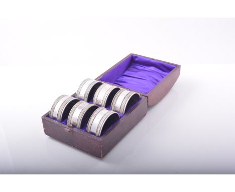 A set of six Edwardian electroplated napkin rings, engine turned, in a fitted morocco case.