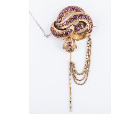 A Victorian yellow metal hollow scrolling ribbon design brooch, individually set with almandine garnets(24), the ribbon finel