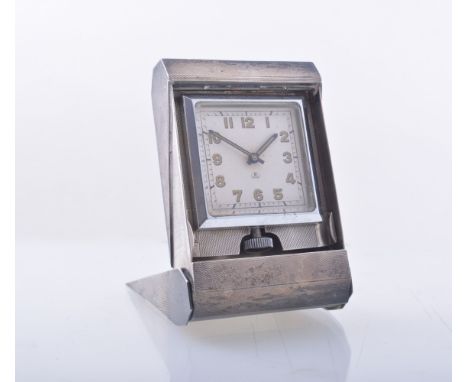 An eight day travel clock in a silver engine turned folding case 95mm x 63mm. Hallmarked Birmingham 1938. Makers mark A Wilco