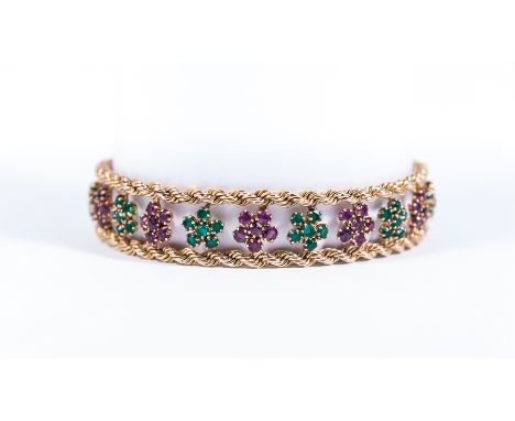 A ruby and emerald yellow metal bracelet, the stones claw set in twenty two circular floral clusters of six stones alternatin