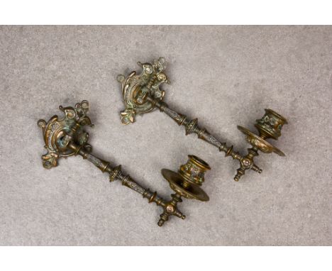 A pair of ornate Victorian bronze pivoted candle wall sconces with shaped and decorated back plates, baluster arms and drip t