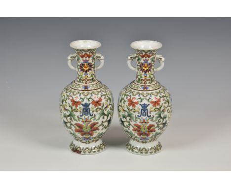 A pair of Chinese enamel vases having twin mask and tongue handles to elongated neck, floral decorated with butterflies on wh