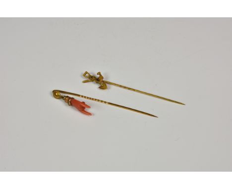 Two Victorian yellow metal stick pins, one marked 'NP' and 'N76', with carved coral hand to terminal; the other with hammer a