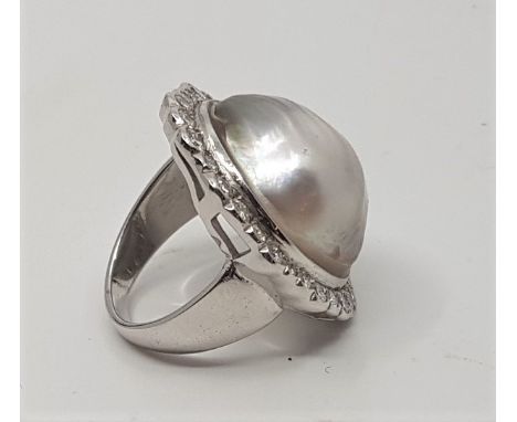 A large 18ct. white gold, diamond and mabe pearl dress ring, the ovoid mount set single large mabe pearl to centre (pearl app