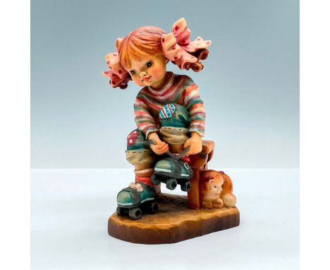 Adorable painted figure of a young girl tying up her roller skates. In hues of earthy green, orange, pink and blue. Anri meta