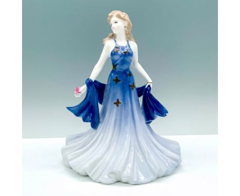 A porcelain figure of a woman dressed in a dark blue dress that fades into lighter colors decorated with butterfly designs an