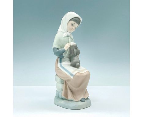 Lovely matte finished porcelain figurine of young woman holding a pet bunny on her lap. Crafted in subtle hues of blue and br