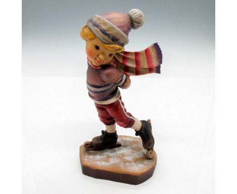 Excellent craftsmanship in this wooden figure of an adorable young boy with his hands covered with mittens behind his back an
