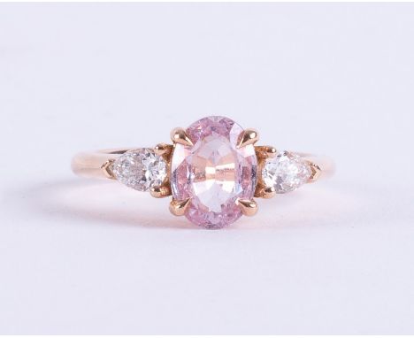 An 18ct rose gold ring set with a central oval cut pale pink sapphire, approx. 1.00 carat, with a pear shaped diamond to each